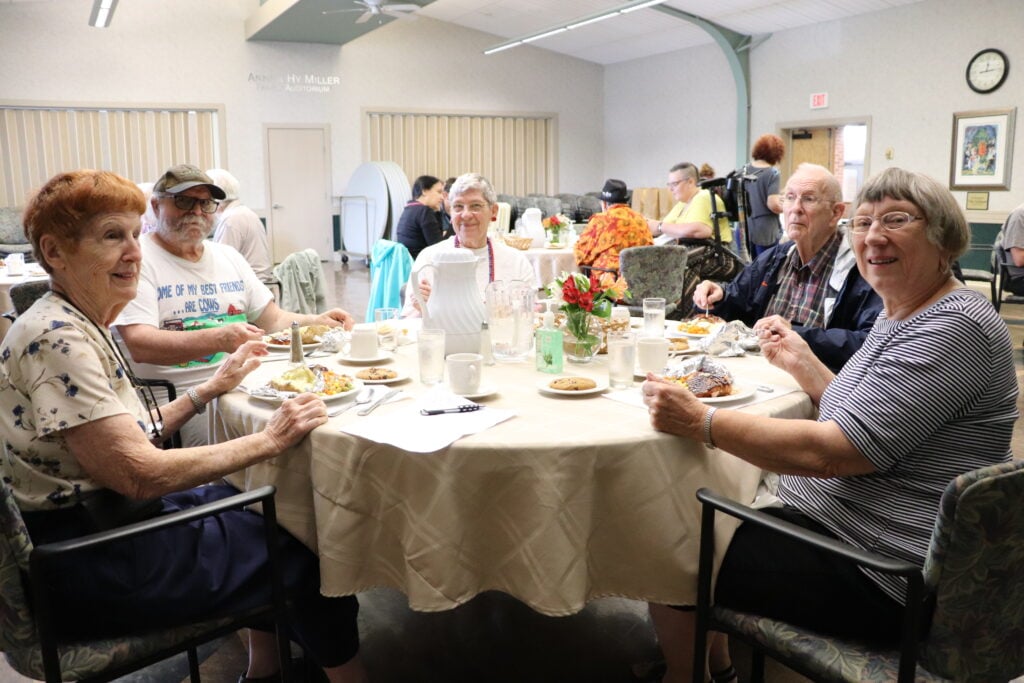 Group of seniors sit around a table at the JCC dining room