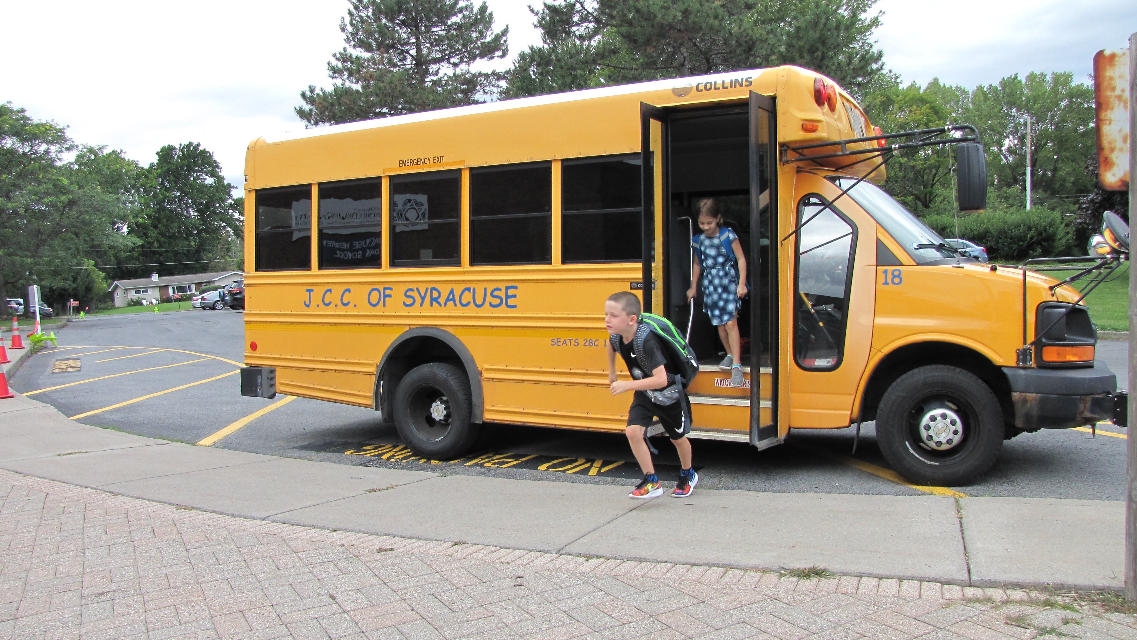 Kids run off a bus to the JCC